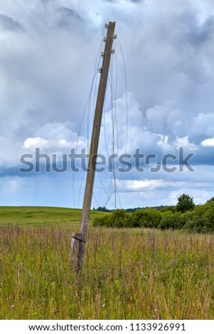 Wooden electric pylon in summer field de-energized wires are broken and hanging in air, power failure, power outage, blokaut. Royalty-Free Stock Photo #1133926991
