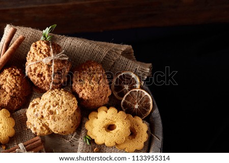 Conceptual composition with assortment of cookies and cinnamon with napkin on a wooden barrel, selective focus
