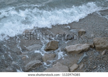 sea wave with foam beats on the rocks on the shore