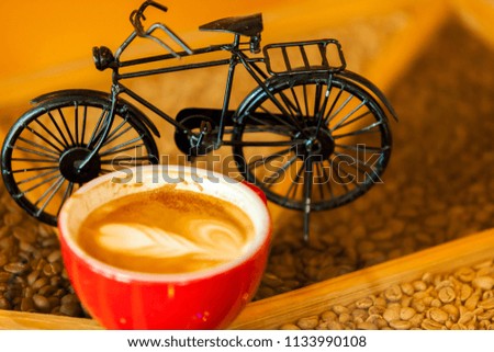 Cup of hot latte art coffee selective blur focus with bicycle toy for decorate woodden table