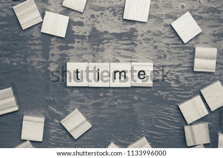 Time word laid out with wooden letters of the alphabet concept on a blue background