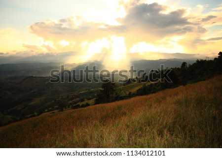 Dramatic god lights passing through clouds and shining on mountain ranges. warm light shower. God hope and dream concept