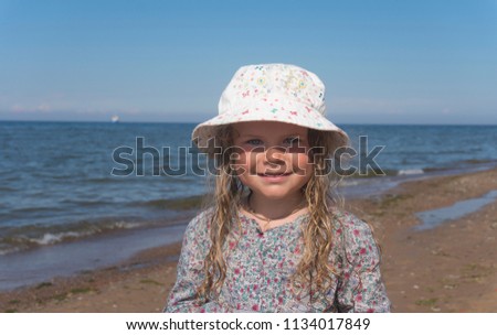 Little girl with blue eyes and long hair on the beach