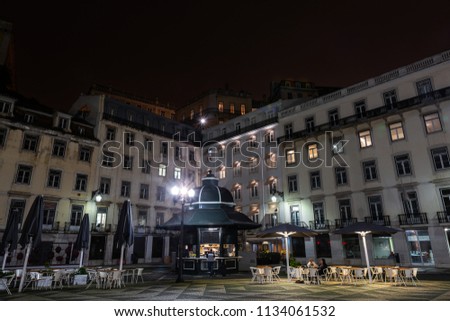Unrecognizable people on a food kiosk and terrace in the Praça do Municipio square in downtown Lisbon on a clear Winter night.