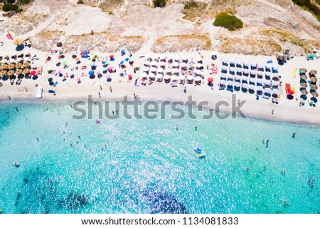 Aerial view of an emerald and transparent Mediterranean sea with a white beach full of beach umbrellas and tourists who relax and take a bath. Gulf of the Great Pevero, Costa Smeralda,Sardinia, Italy.