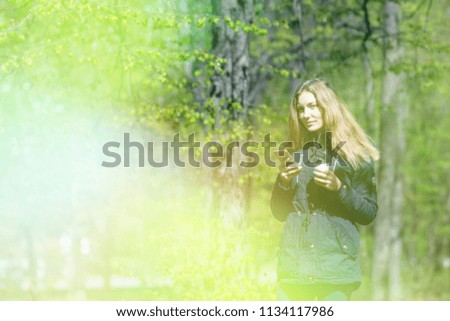 A girl is walking in the morning in a park with a smartphone and coffee