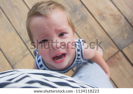 crybaby. The little boy is holding his mother's leg and crying loudly. Royalty-Free Stock Photo #1134118223