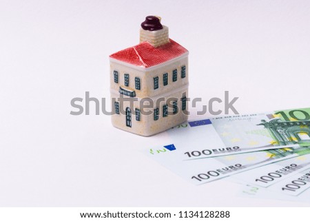 Miniature toy house model and euro banknote on white background