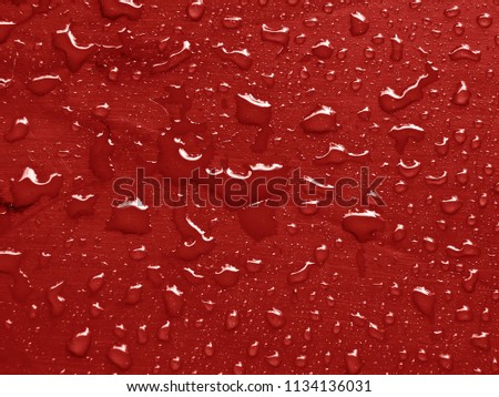 water drops on valiant poppy colored metallic surface