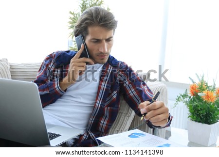 young man working with financial documents sitting on sofa in living room