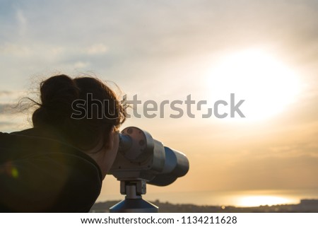 A girl looks through panoramic binoculars on a viewing platform
