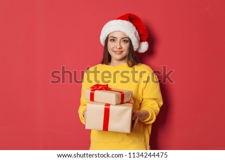 Young woman with Christmas gifts on color background