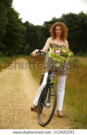 Young woman standing with her bike on the pathway
