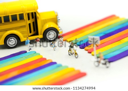 Miniature people : cycling of school bus  with Colorful ice cream sticks background.