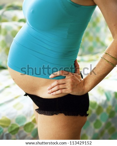Pregnant woman's torso in blue vest and black panties