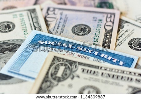 USA social security cards and dollar bills. Money in retirement concept. Blurred photo with selective focuse