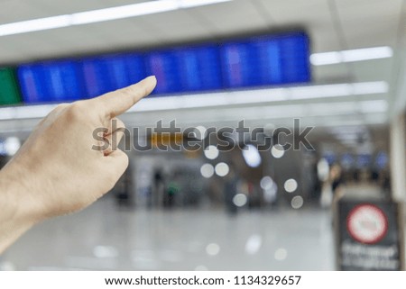 Finger of man is pointing at blur flight schedule for check timetable to departure in non smoking area at international airport terminal with copy space.