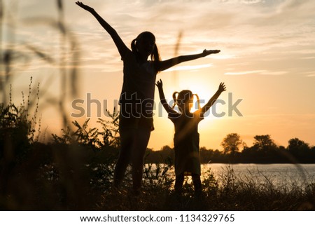 Family of parents and children silhouettes at sunset outdoors