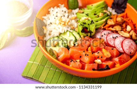 Hawaiian salad Poke with salmon fish, avocado, Korean carrots, cucumbers, radish and rice, with black sesame. in an orange plate. On the purple trend background of 2018. copy space, top view