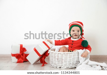 Cute little baby wearing Christmas costume in basket at home