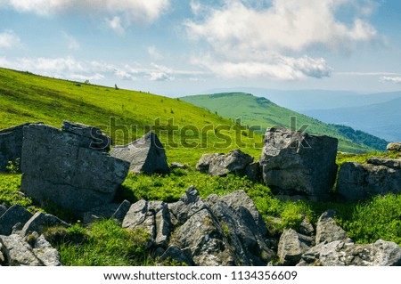 huge rocky formations on the grassy hills. beautiful mountain landscape in late summer on a cloudy day. location Runa mountain, Ukraine