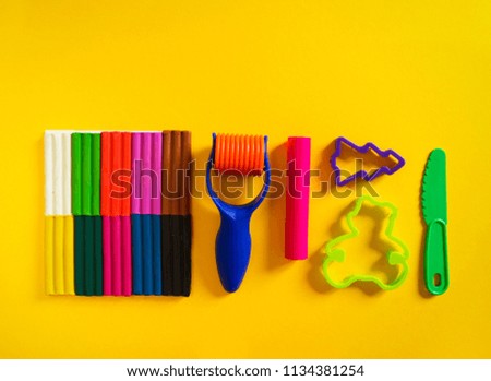 Tools for creative hobbies. Molding of plasticine, stack, shape, rolling pin. Easy education, school, kindergarten. Yellow background.
