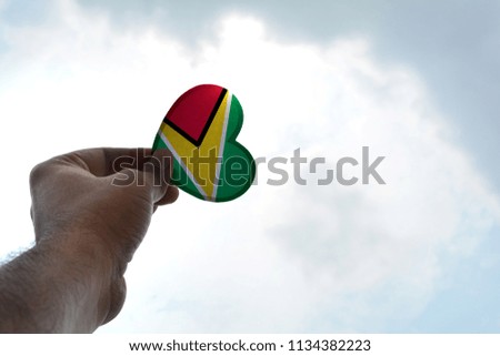 Hand holds a heart Shape Guyana flag