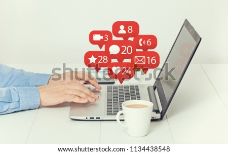 man working on laptop at office and notification icons of social network flying over laptop