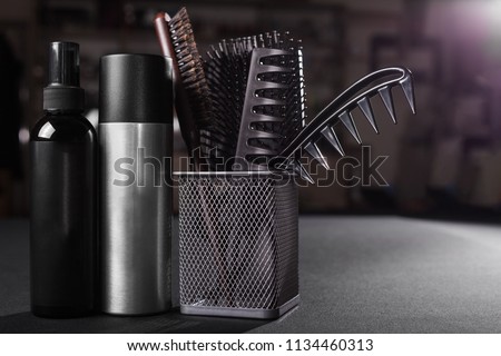two flacons of professional hair sprays near a basket with hairbrushes standing on a table in a salon. concept of hair caring tools. free space for advertising Royalty-Free Stock Photo #1134460313
