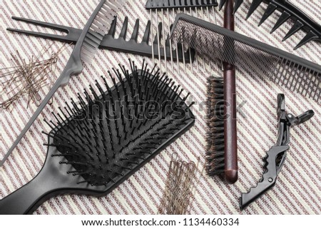 set of various hairbrushes, hairpins and hair sticks lying on a grey striped background. concept of professional hairdresser tools