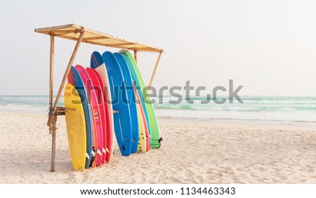 Set of different color surf boards in a stack by ocean. Weligama, SRI LANKA. Surf boards for rent on sandy beach. Soft toned photo. Royalty-Free Stock Photo #1134463343