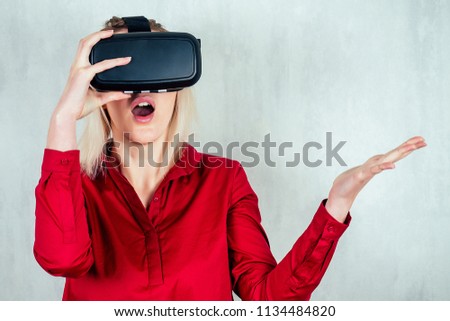 A white girl in a red shirt and virtual reality glasses is very much surprised