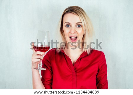 happy blonde woman in red shirt holds a glass of wine in hands
