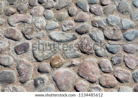 Grey cobblestone texture of the ground with many stones as background or road.