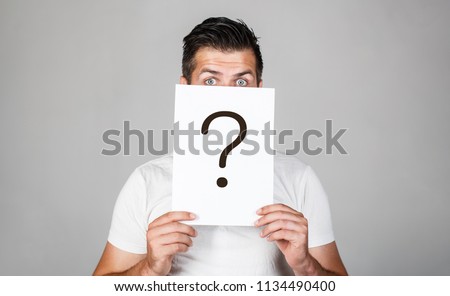 Question mark, symbol. Pensive male. Man a question. Doubtful man holding Question Mark. Problems and solutions. Getting answers. Portrait of man, peeking behind of interrogation symbol. Male isolated