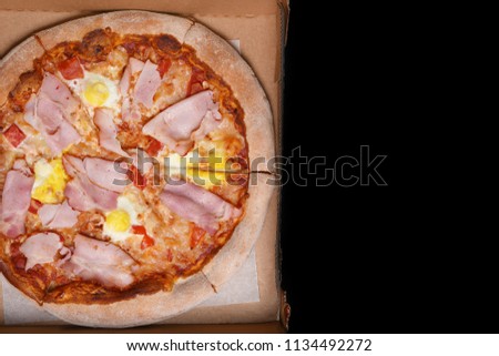 pizza in cardboard delivery box against black background