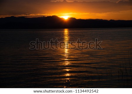 Sunrise on the lake. Early morning landscape. mountain in silhouettes and the rays of the rising sun.Sunrise on Lake Garda, Italy.