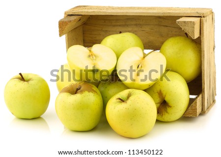 fresh "Golden Delicious" apples and a cut one in a wooden crate  on a white background