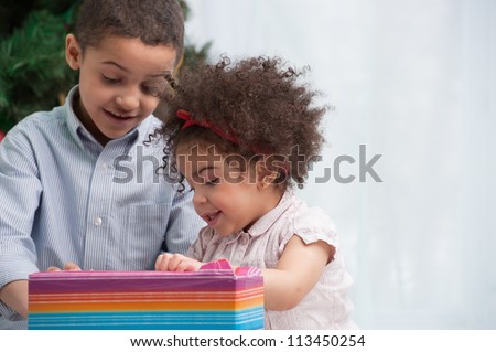 Happy children holding Christmas gifts and sitting on the floor Royalty-Free Stock Photo #113450254