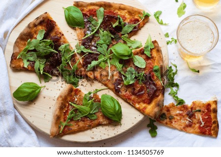 flat lay of homemade delicious pizza and beer on wooden board over white tablecloth background    