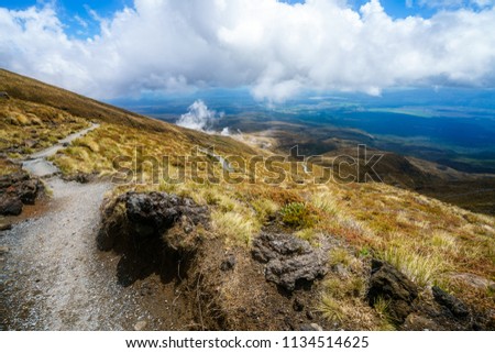 hiking the tongariro alpine crossing,smoke in volcanic crater, grass and lake in the background, volcano,new zealand