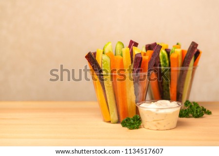 colorful carrots and cucumbers vegetables julienned in plastic cups and sour cream dip decorated parsley over wooden board