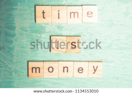 Time is money words laid out with wooden letters of the alphabet concept on a blue background