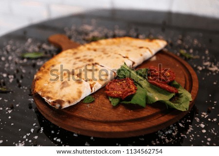 Sliced calzone pizza on a rustic wooden serving tray, selective focus