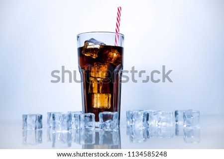 A refreshing drink of stake is poured into a glass beaker with a tube. White background with scattered ice cubes.
