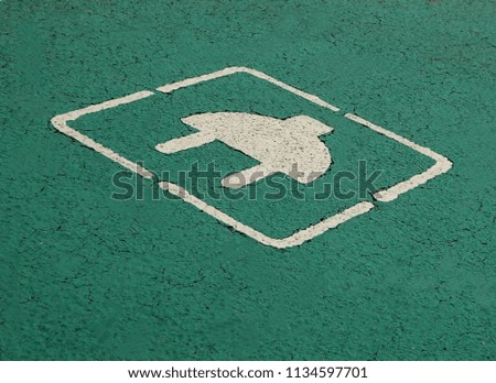 Electric car parking and charging sign. White plug painted on green background in the asphalt