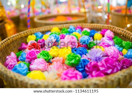 Colorful ribbon flowers that contain a coin inside for giving alms to in the ceremony when a man become a monk. Religion concept, Colorful Artificial Ribbon Rose in the basket, selective focus