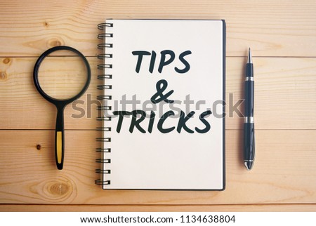 Tips and tricks text on notepad with pen and magnifying glass                         