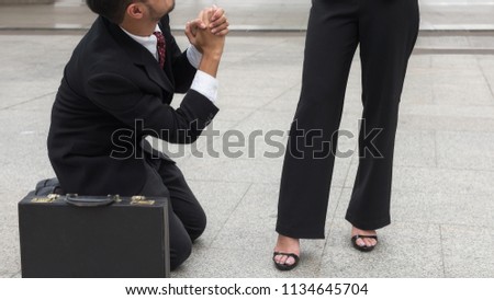 Sad Business man  kneel and raise hands to ask for sympathy after he not get promote or be punished outside office building. Work in pressure concept with copy space for text.
