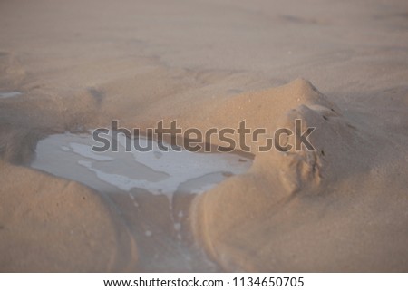beach abstract macro photography - falling apart flooded sand construction with foam and water, on Atlantic shore in the Gambia, on a sunny summer day